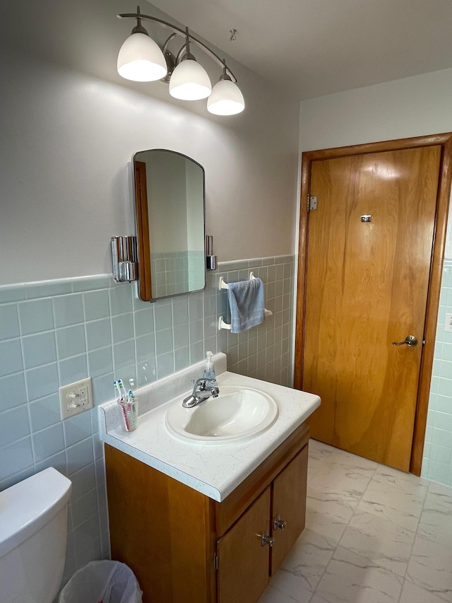 bathroom with vanity, tile walls, and toilet