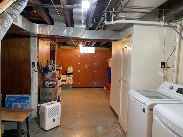 basement with washer and clothes dryer and wood walls