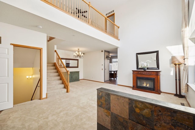 living room featuring light carpet, a towering ceiling, and a chandelier