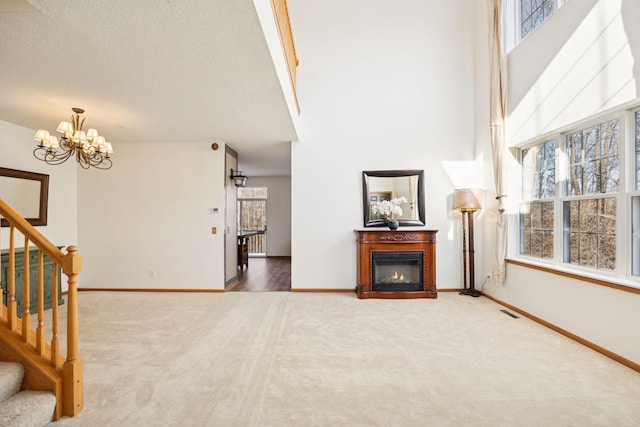 carpeted living room with a towering ceiling, a textured ceiling, and a notable chandelier