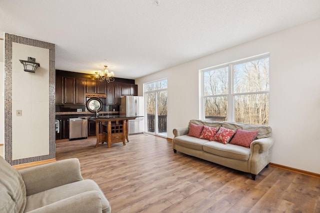 living room featuring sink, a chandelier, and light wood-type flooring