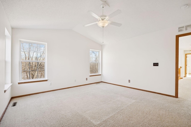 carpeted empty room with ceiling fan, lofted ceiling, and a textured ceiling