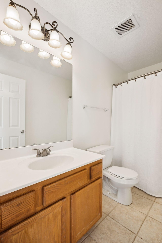 bathroom with tile patterned floors, vanity, toilet, and a textured ceiling