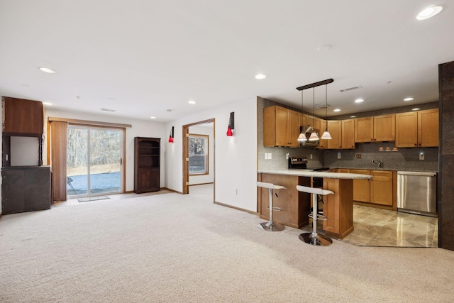 kitchen with decorative light fixtures, appliances with stainless steel finishes, a kitchen breakfast bar, light colored carpet, and decorative backsplash