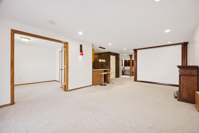 unfurnished living room featuring indoor bar and light carpet