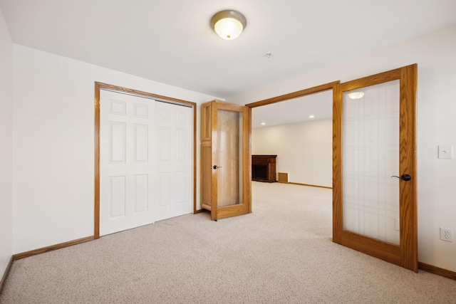 unfurnished bedroom with french doors, a closet, and light carpet