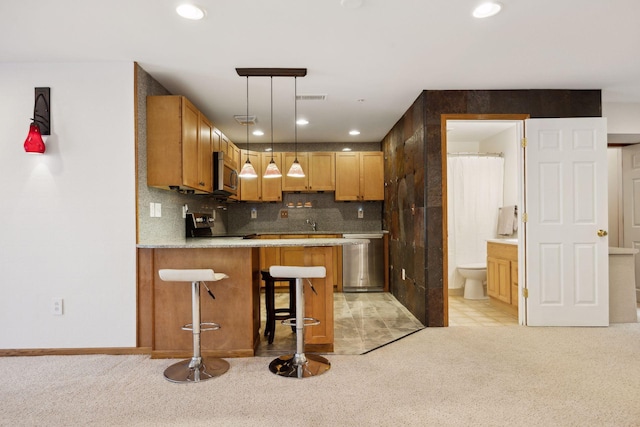 kitchen featuring a breakfast bar area, appliances with stainless steel finishes, backsplash, hanging light fixtures, and kitchen peninsula