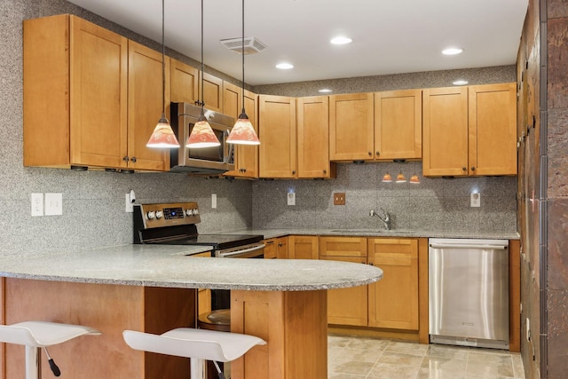 kitchen with sink, a breakfast bar area, appliances with stainless steel finishes, backsplash, and kitchen peninsula