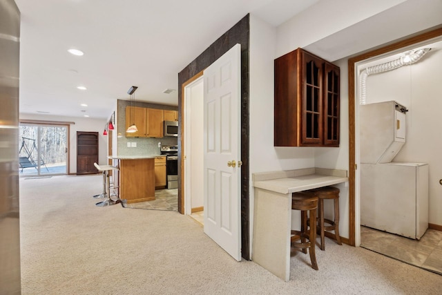 kitchen with appliances with stainless steel finishes, a kitchen breakfast bar, tasteful backsplash, decorative light fixtures, and kitchen peninsula