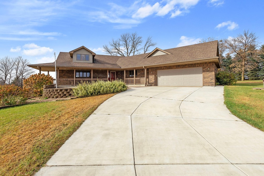 view of front of property featuring a front lawn, a porch, and a garage