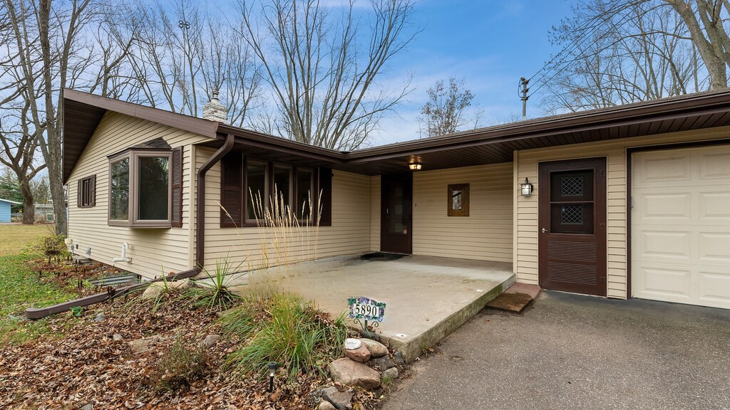 ranch-style house with an attached garage, a chimney, and aphalt driveway