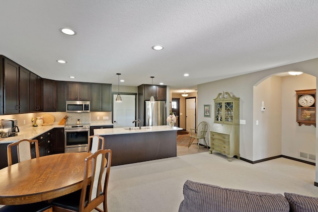 kitchen with sink, appliances with stainless steel finishes, tasteful backsplash, decorative light fixtures, and a kitchen island