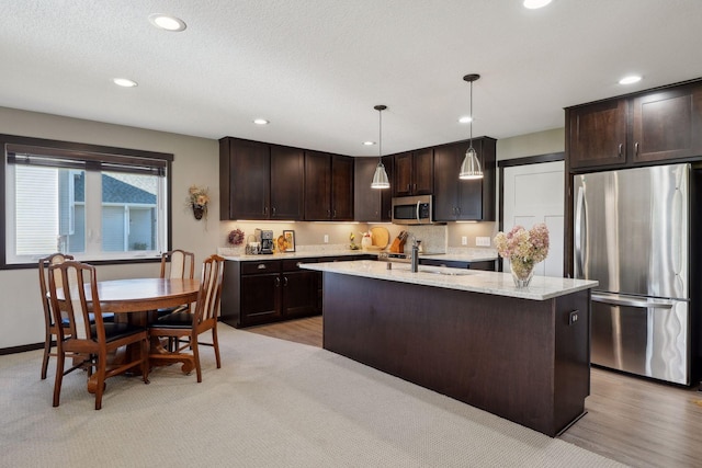 kitchen with hanging light fixtures, sink, stainless steel appliances, and dark brown cabinets