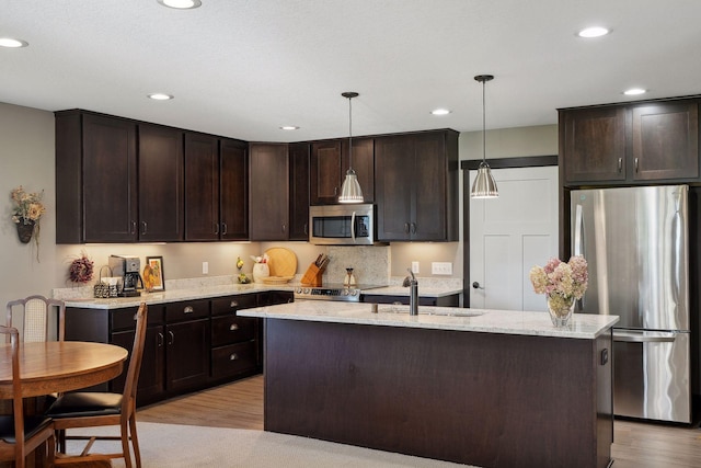 kitchen with pendant lighting, light hardwood / wood-style floors, dark brown cabinetry, and appliances with stainless steel finishes