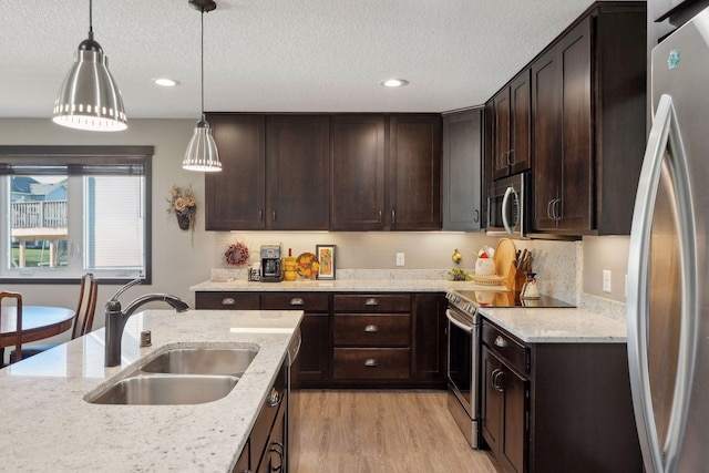 kitchen featuring pendant lighting, sink, appliances with stainless steel finishes, dark brown cabinets, and light stone counters