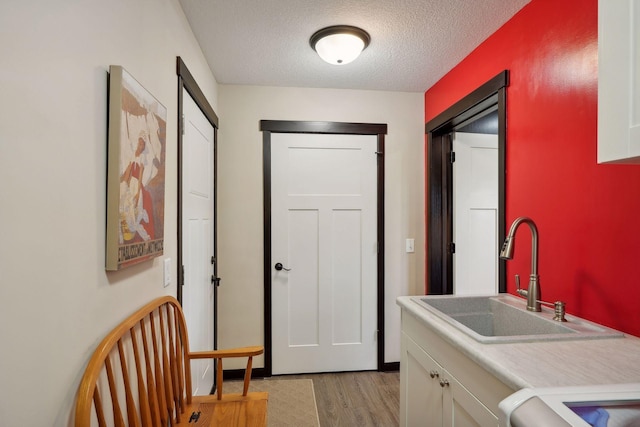 hallway featuring light wood-type flooring, a textured ceiling, and sink