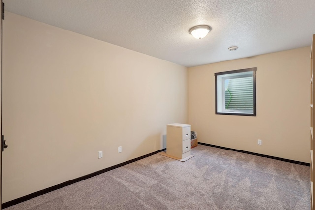 spare room featuring light carpet and a textured ceiling