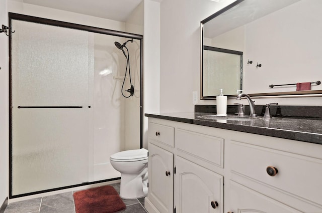 bathroom featuring tile patterned floors, vanity, toilet, and a shower with door