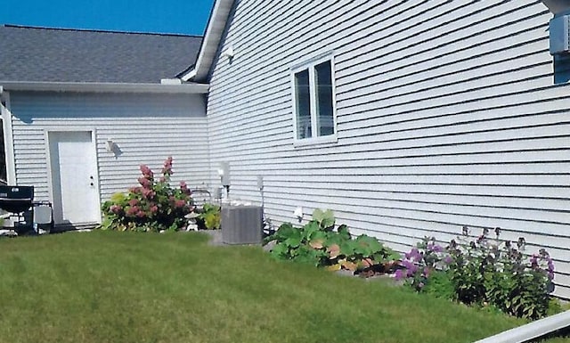 view of home's exterior with a lawn and central AC unit