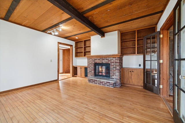 unfurnished living room with a fireplace, wood ceiling, built in features, and beamed ceiling