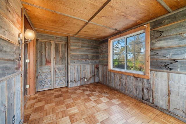 spare room with wooden walls, light parquet floors, and wooden ceiling