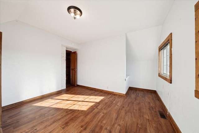 spare room featuring lofted ceiling and hardwood / wood-style flooring