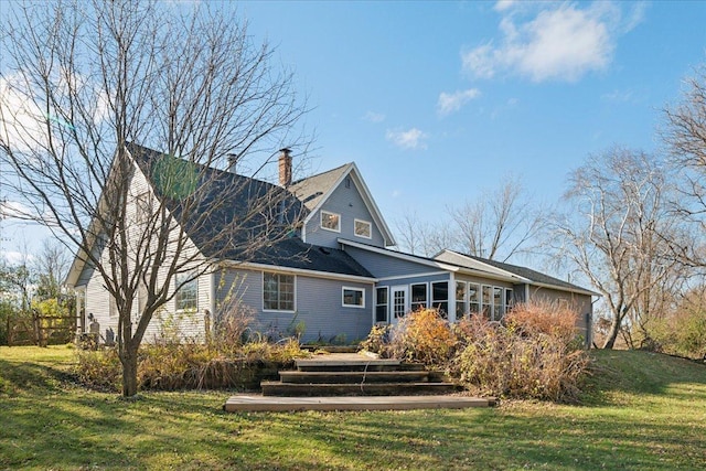 rear view of house featuring a sunroom and a yard