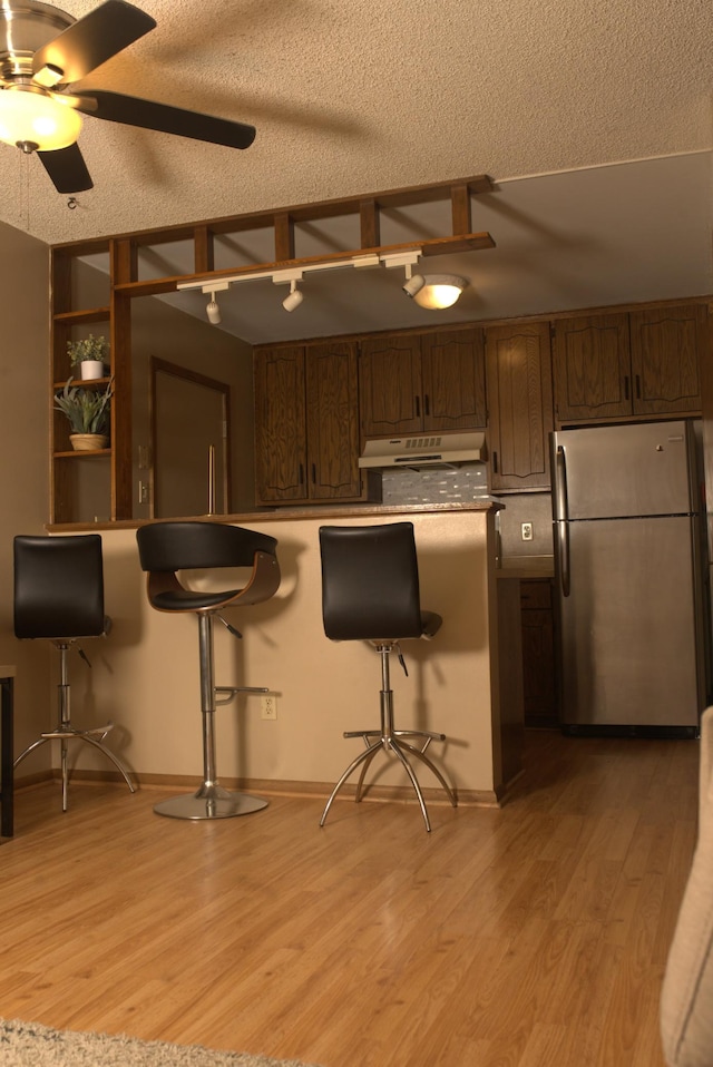 kitchen with stainless steel fridge, a breakfast bar, and light hardwood / wood-style floors