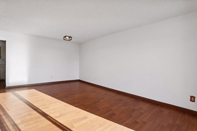 unfurnished room with a textured ceiling and dark hardwood / wood-style flooring