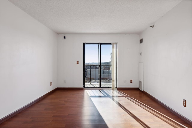 empty room with dark hardwood / wood-style floors and a textured ceiling