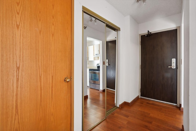 hall with a textured ceiling and dark hardwood / wood-style floors