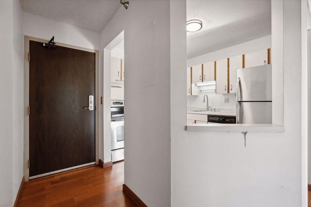 corridor with dark hardwood / wood-style floors, a textured ceiling, and sink