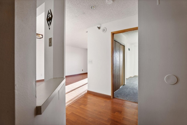 hallway with hardwood / wood-style floors and a textured ceiling