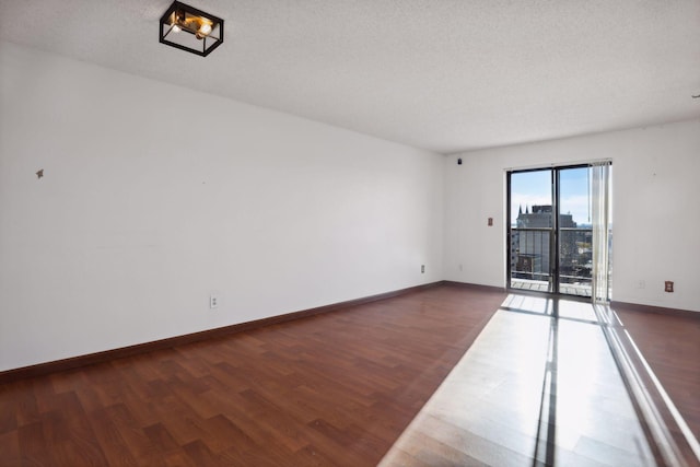 unfurnished room featuring a textured ceiling and dark hardwood / wood-style floors