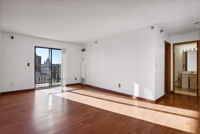 empty room featuring sink, wood-type flooring, and a textured ceiling