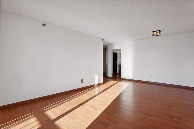 spare room with a textured ceiling and dark hardwood / wood-style floors