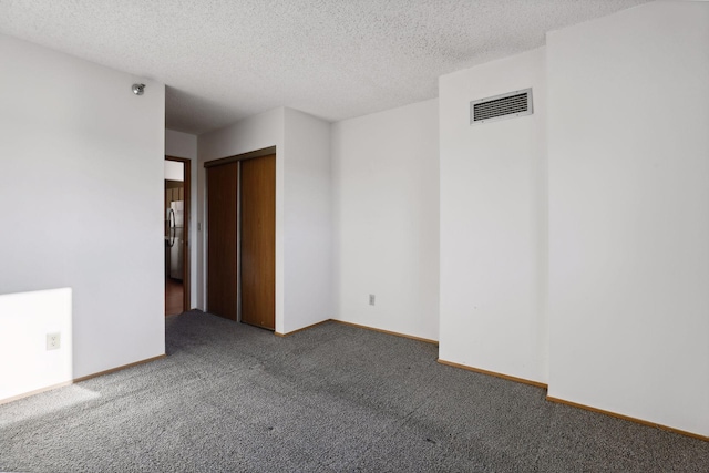 carpeted empty room featuring a textured ceiling