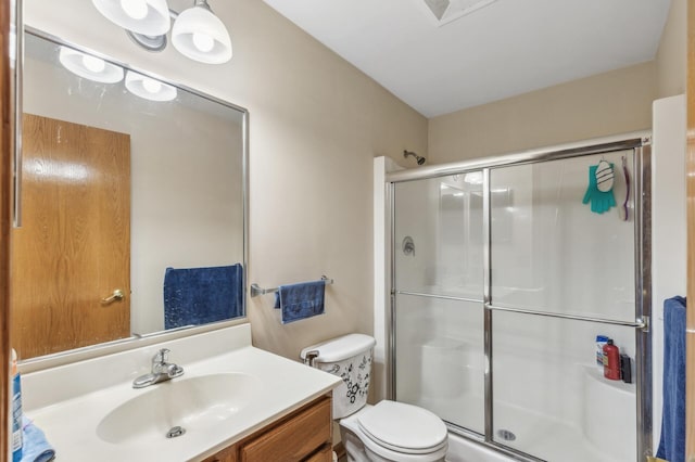 bathroom featuring vanity, an enclosed shower, and toilet