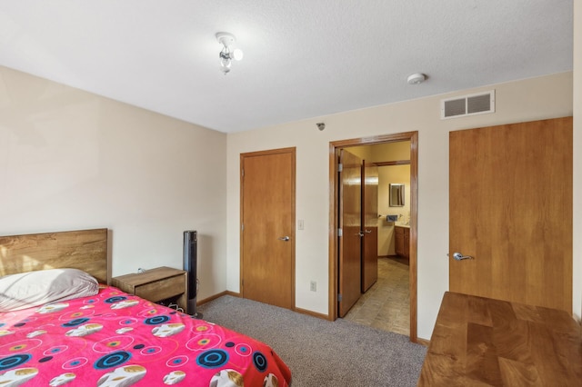 carpeted bedroom with a textured ceiling, ensuite bathroom, and a closet