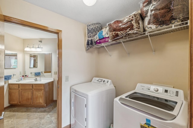 clothes washing area featuring a textured ceiling, washing machine and dryer, and sink