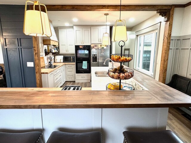 820 Labree Ave N, Thief River Falls, MN 56701 - kitchen with wood counters, black appliances, wood finished floors, a sink, and custom exhaust hood