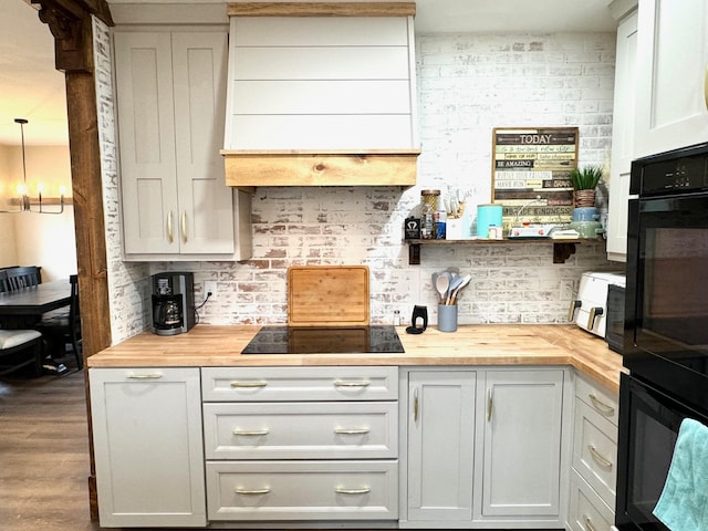 kitchen with wooden counters, black appliances, a notable chandelier, dark hardwood / wood-style floors, and decorative light fixtures