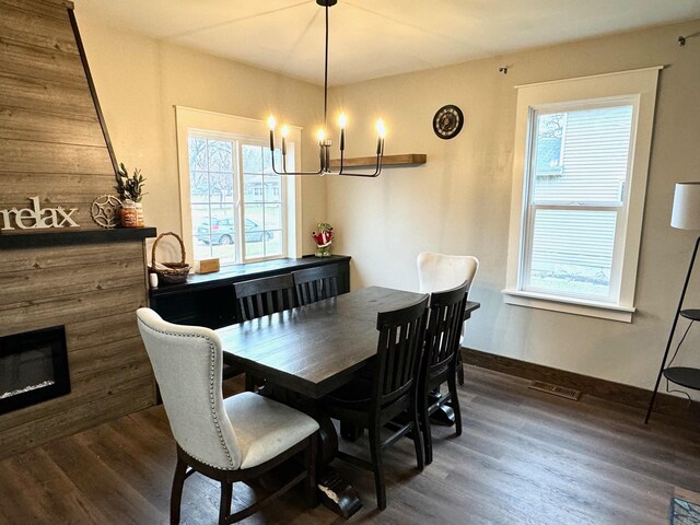 820 Labree Ave N, Thief River Falls, MN 56701 - dining room featuring a chandelier, dark wood-style flooring, healthy amount of natural light, and a glass covered fireplace