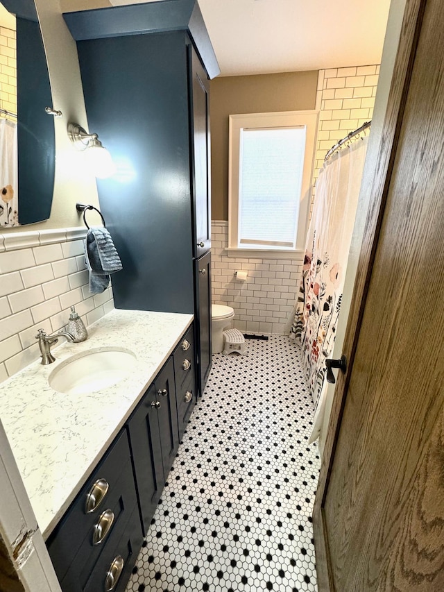 820 Labree Ave N, Thief River Falls, MN 56701 - bathroom with tile walls, vanity, a wainscoted wall, toilet, and curtained shower