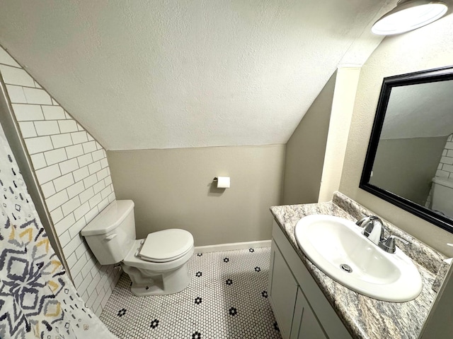 bathroom with toilet, vanity, lofted ceiling, and tile patterned floors