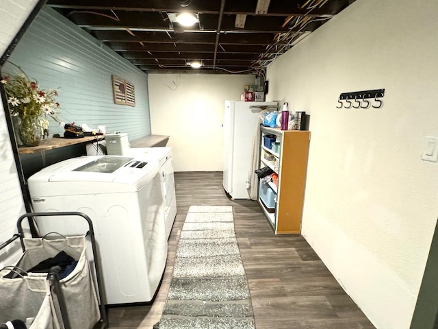 clothes washing area with dark wood-type flooring, separate washer and dryer, and wooden walls