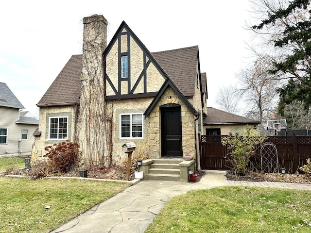 820 Labree Ave N, Thief River Falls, MN 56701 - tudor house with a shingled roof, stone siding, and a chimney