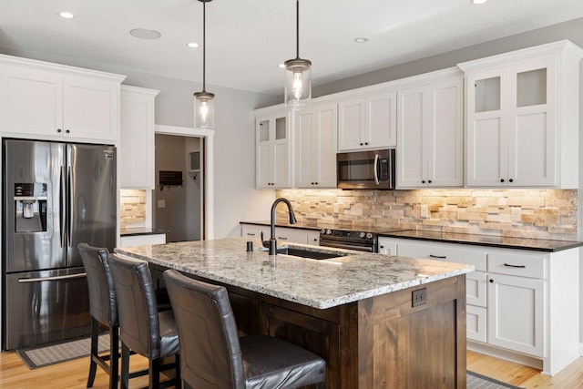 12770 196th Ave NW, Elk River, MN 55330 - kitchen with appliances with stainless steel finishes, a sink, backsplash, a center island with sink, and light wood finished floors