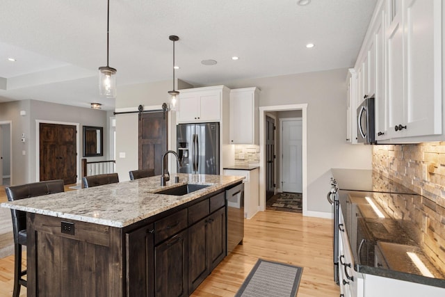 12770 196th Ave NW, Elk River, MN 55330 - kitchen featuring appliances with stainless steel finishes, a sink, a barn door, a breakfast bar, and decorative backsplash