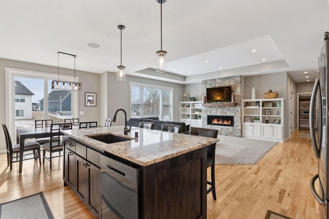 12770 196th Ave NW, Elk River, MN 55330 - kitchen with a sink, a tray ceiling, dark brown cabinets, light wood-style flooring, and a fireplace